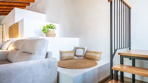 Een moderne woonkamer met een bank, een rond vloerkleed, een plant en een trap met houten treden.