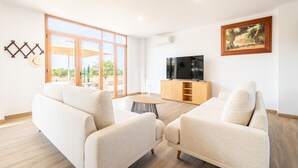Een moderne woonkamer met twee banken, een televisie en een schilderij aan de muur.