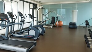 A gym with treadmills, elliptical machines, a rowing machine, and dumbbells.