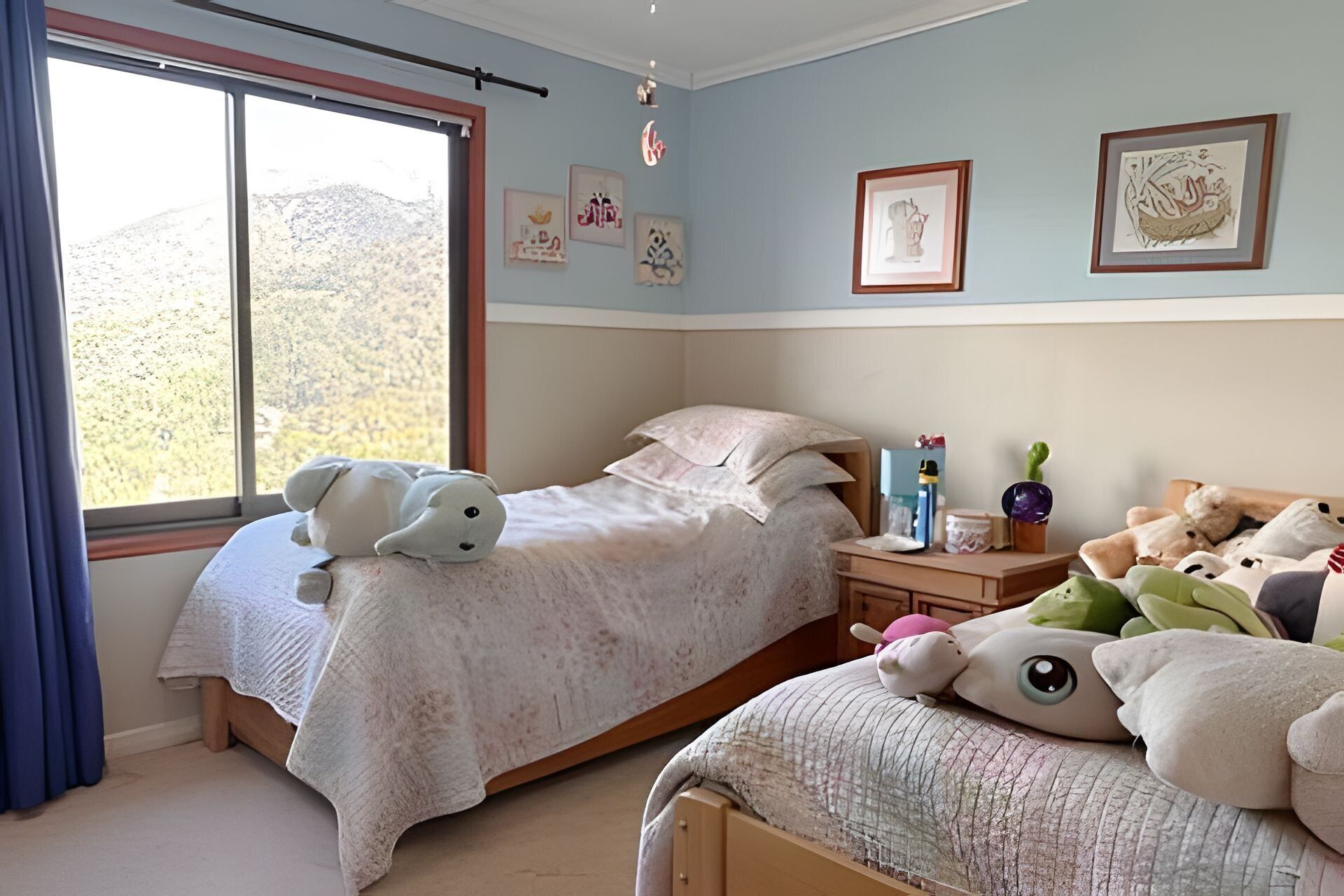 A bedroom with two beds, a window, and wall art.