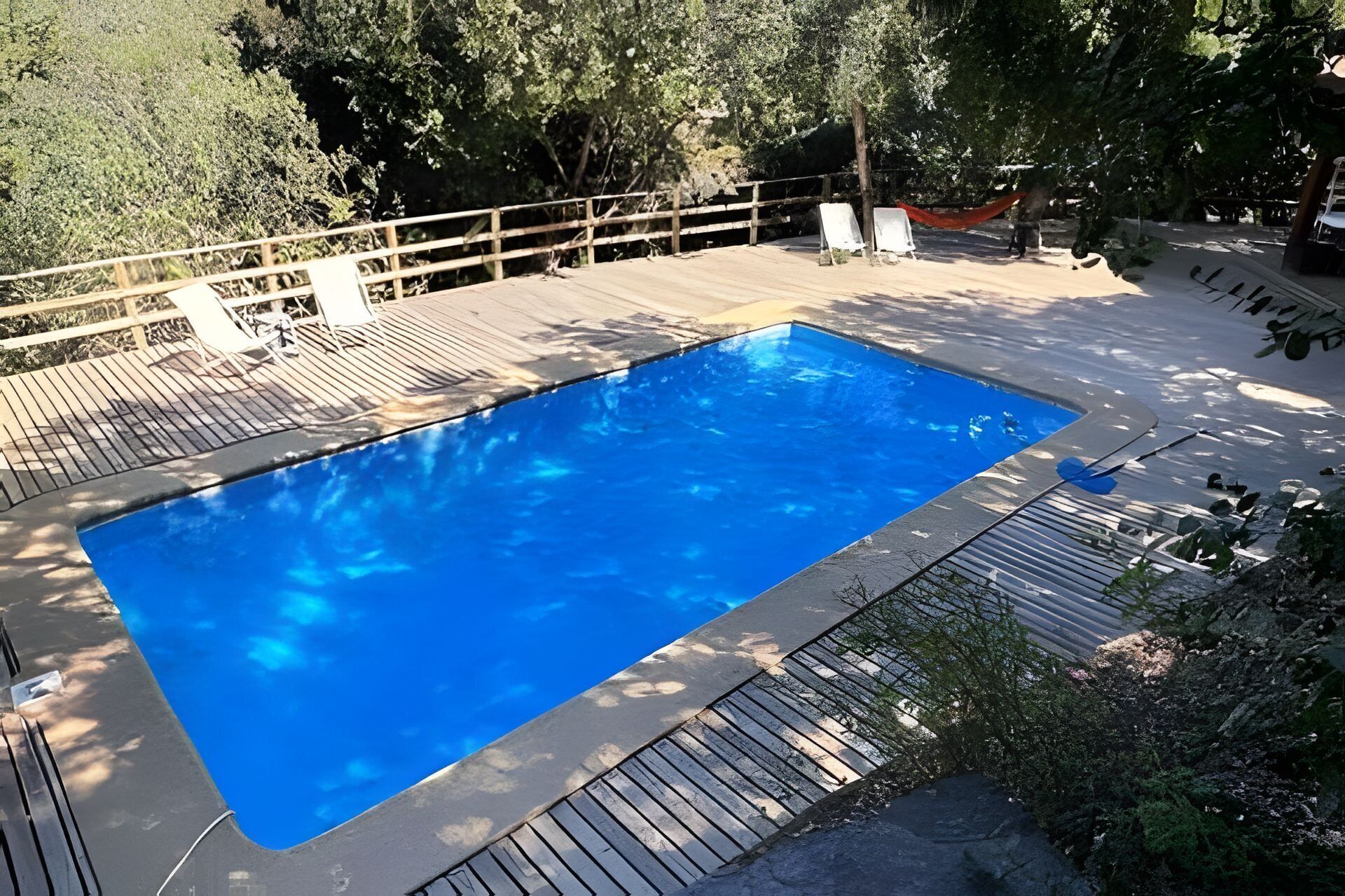 Uma piscina retangular com um deck de madeira ao redor.