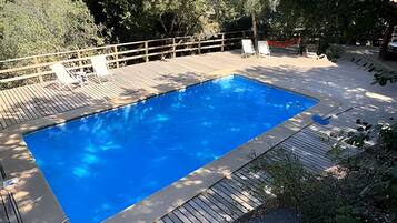 Uma piscina retangular com um deck de madeira ao redor.