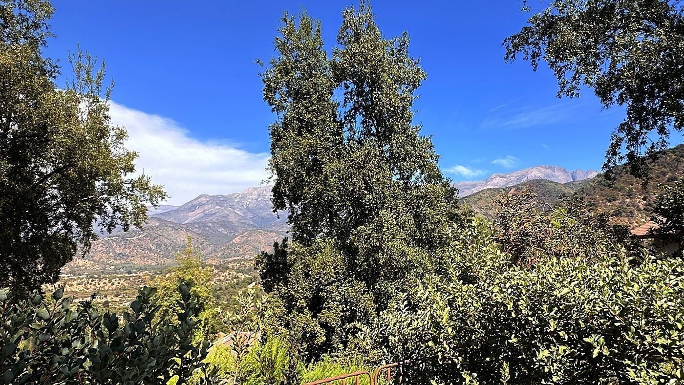 A mountainous landscape with dense foliage and a clear sky.