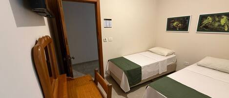 Ein Hotelzimmer mit zwei Betten, einem Holztisch und einem Stuhl.