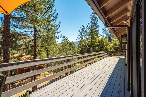 A wooden deck with a railing overlooking a forested area.