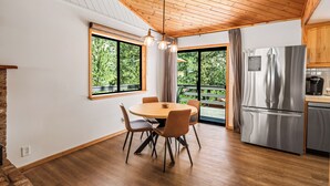 Una cocina moderna con techo de madera, ventanas amplias y un refrigerador de acero inoxidable.