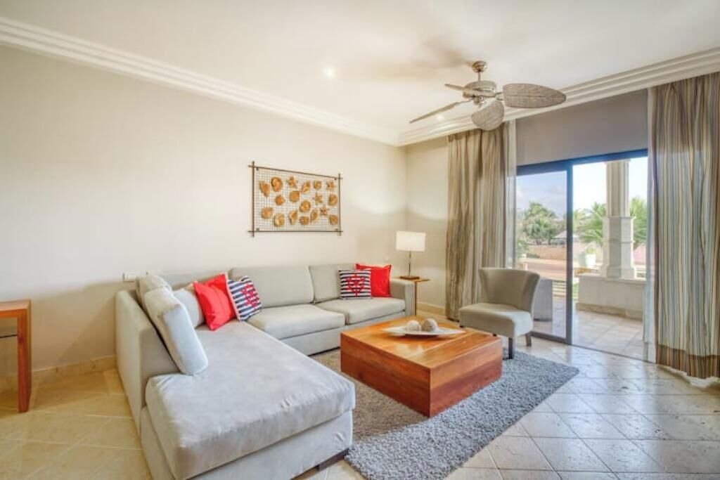 A modern living room with a grey sectional sofa, a wooden coffee table, a floor lamp, and a ceiling fan.