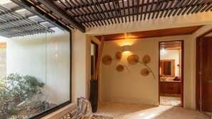 A modern interior with a glass wall, a wooden ceiling, and a stone pathway leading to a bathroom. - Green Village 2BDR villa w/ pool (La Altagracia)