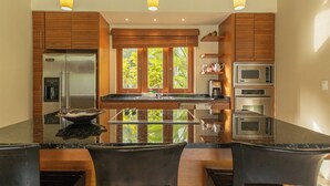 A modern kitchen with wooden cabinets, stainless steel appliances, and a central island. - Green Village 2BDR villa w/ pool (La Altagracia)
