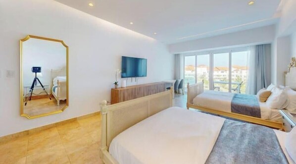 Een moderne hotelkamer met een groot bed, een bureau, een televisie en een groot raam met uitzicht op de stad.