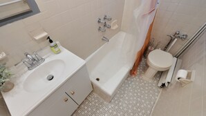Une salle de bain équipée d’un lavabo, d’une baignoire, de toilettes et d’un rideau de douche.