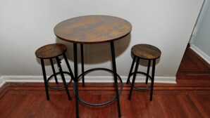 Une table ronde en bois, accompagnée de trois tabourets.