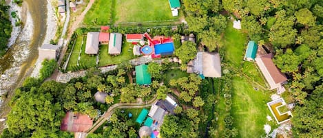 An aerial view of a resort with multiple buildings, a swimming pool, and lush greenery.