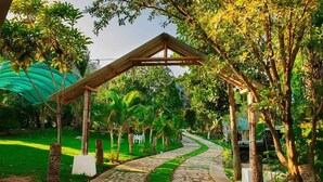 Un sendero serpentea por un exuberante jardín con una estructura de pérgola de madera.