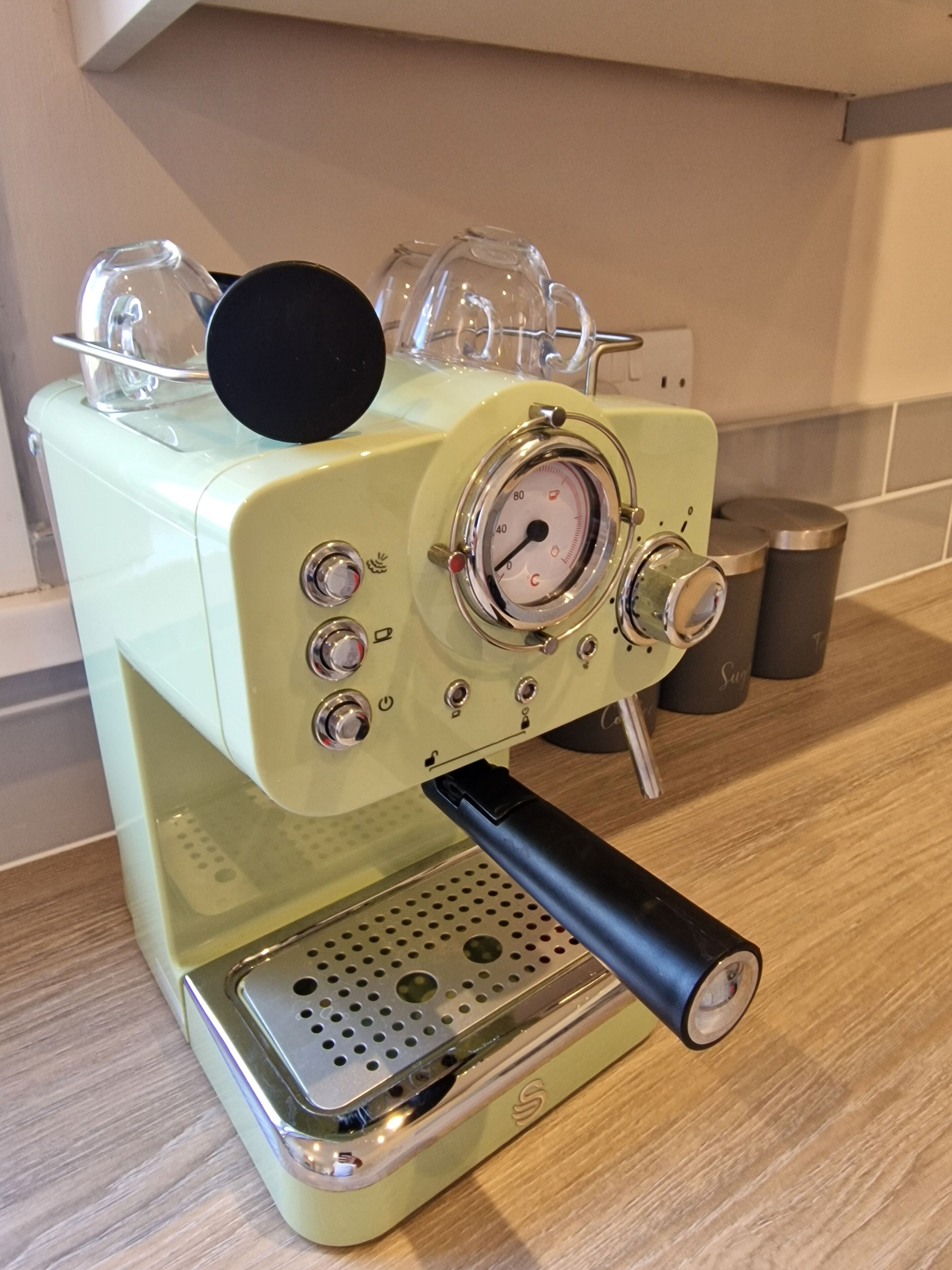 A vintage espresso machine with a digital pressure gauge, a steam wand, and a portafilter.