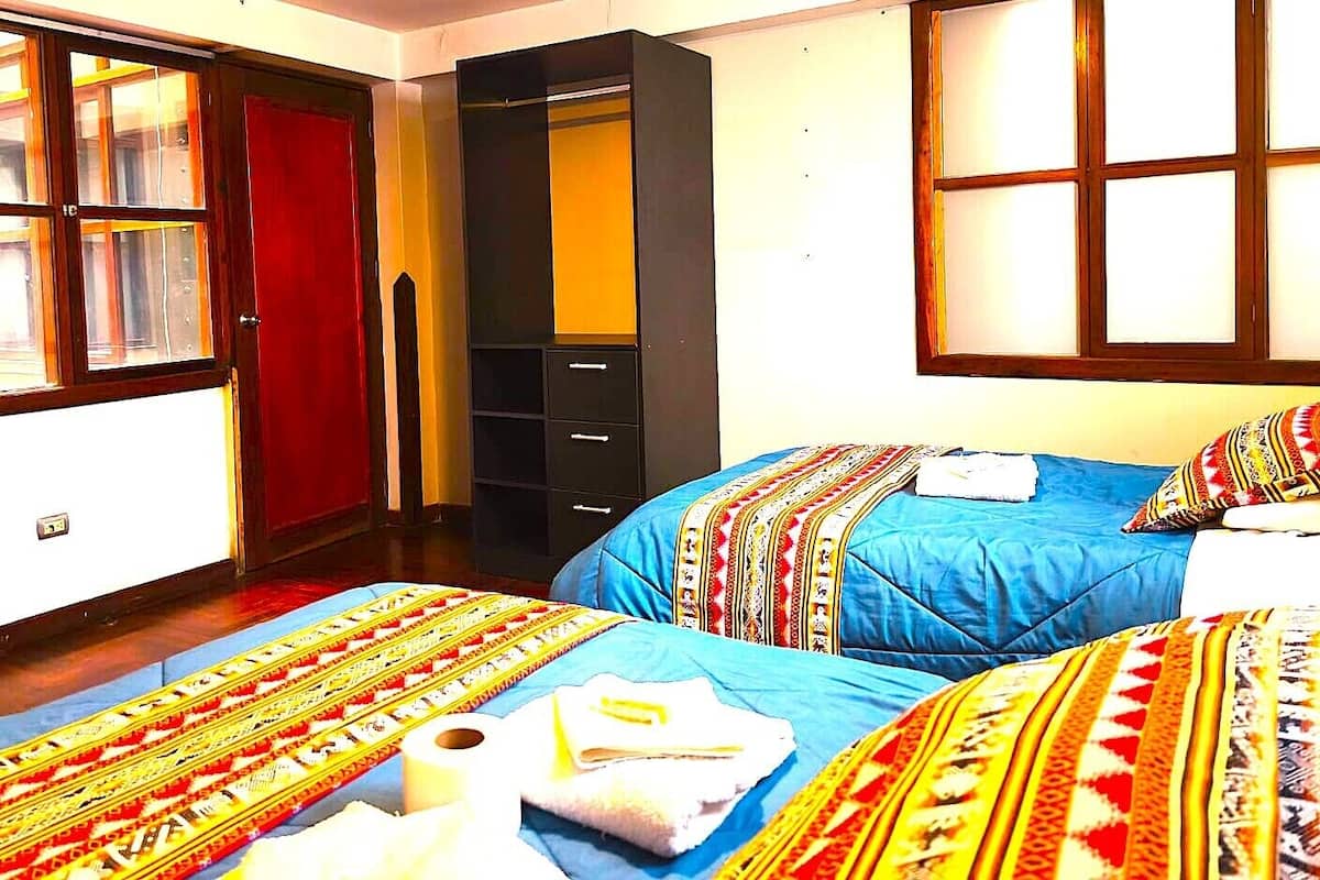 Une chambre d’hôtel avec deux lits, une armoire et une fenêtre.