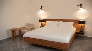 A hotel room with a wooden bed, two bedside lamps, a small round table, and a chair.