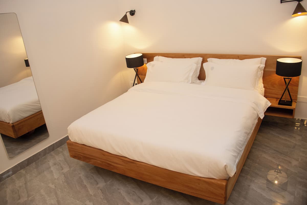 A modern bedroom with a wooden bed, two bedside lamps, and a mirror on the wall.