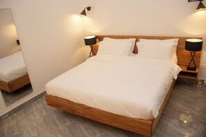 A modern bedroom with a wooden bed, two bedside lamps, and a mirror on the wall.