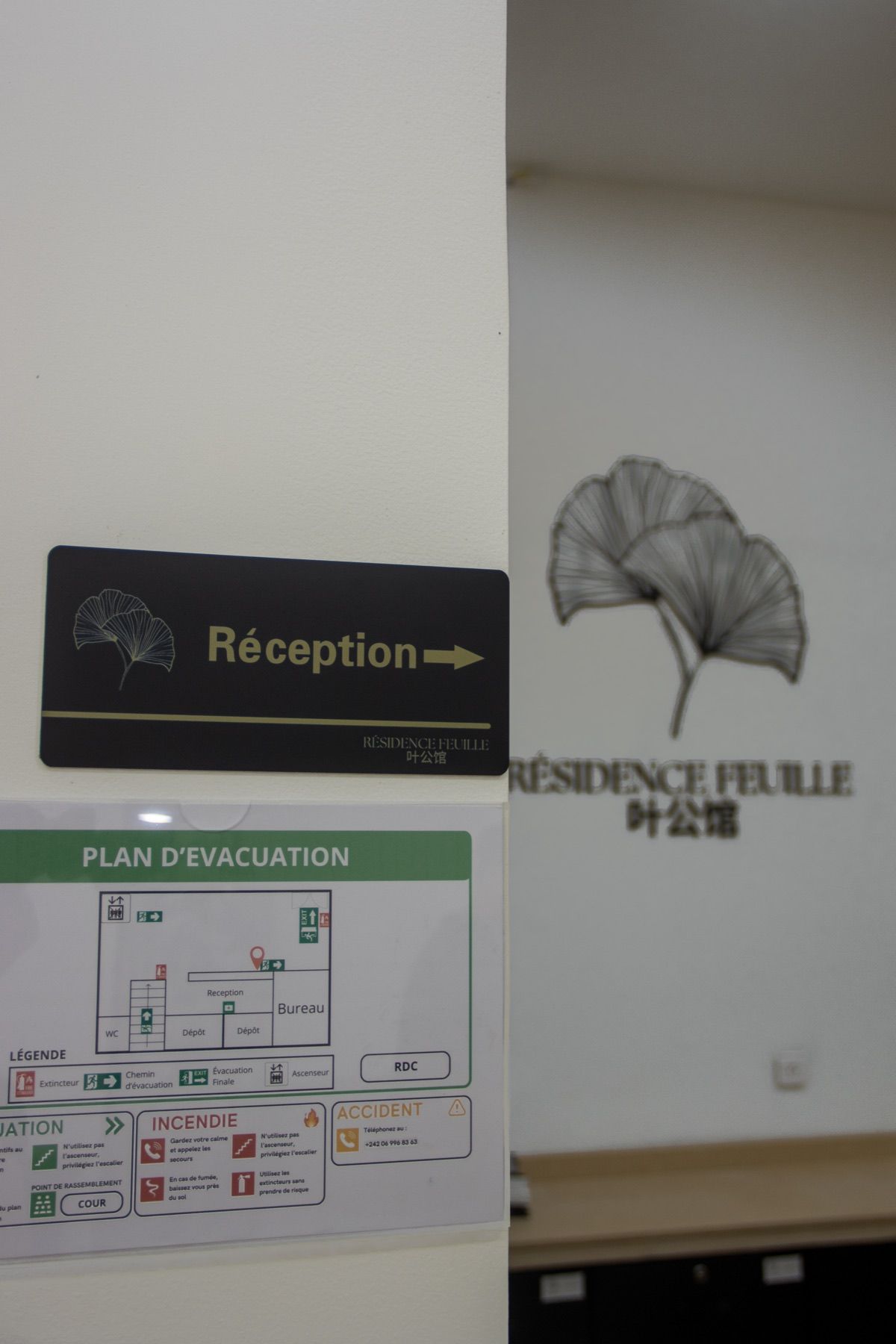 A reception sign with an evacuation plan and a logo for Residence Feuille.