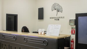 Una reception con una insegna che riporta "Résidence Feuille" e un estintore appeso al muro.