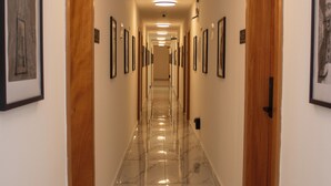 Un corridoio con quadri appesi alle pareti, porte in legno e un pavimento in marmo.