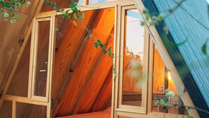 A cozy attic bedroom with a sloped ceiling, wooden walls, and a bed with a light-colored blanket.