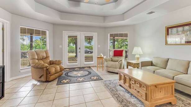 A spacious living room with a ceiling fan, a beige sofa, a recliner, and a wooden coffee table. - Slab Road Hill Country Escape! (Llano County)