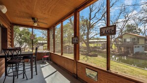 A wooden cabin with a dining area, a view of a lake, and a sign indicating a jump in the lake. - Lakeside Rock house on Lake LBJ! (Llano County)