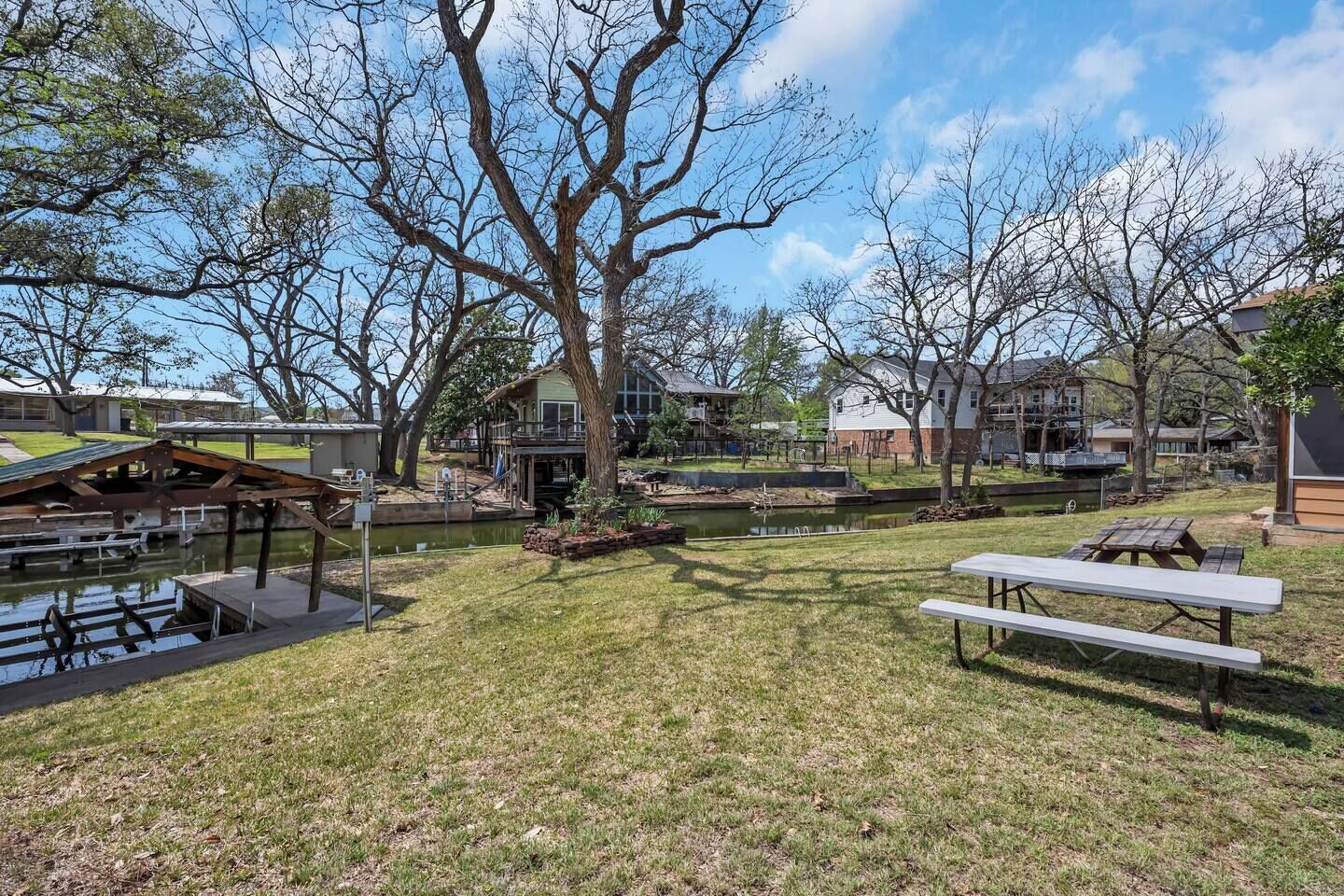 A grassy outdoor area with picnic tables, a small pond, and a gazebo.