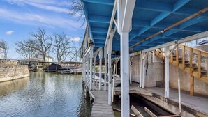Un muelle techado que se extiende sobre un canal, con un pasillo de madera y una estructura de techo azul.