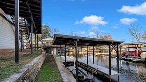 A covered dock extending over a canal with boats docked on the other side. - Lakeside Lounge on Lake LBJ! (Llano County)