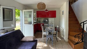 Un espace de vie compact comprenant un canapé, une table à manger et des chaises, un coin cuisine et un escalier.