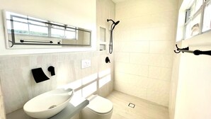 A modern bathroom with a toilet, sink, and shower.