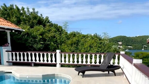 A poolside area with a pool, lounge chairs, and a white balustrade.