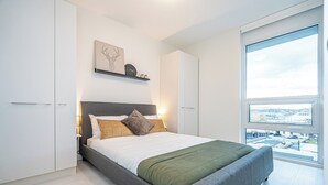 A modern bedroom with a large bed, a view of the city through a large window, and a minimalist design. - Spacious 3-bedroom apartment with AC, WiFi in wonderful Vancouver (Vancouver)