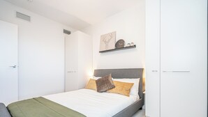 A modern bedroom with a bed, a nightstand, a shelf with decorative items, and a door. - Spacious 3-bedroom apartment with AC, WiFi in wonderful Vancouver (Vancouver)