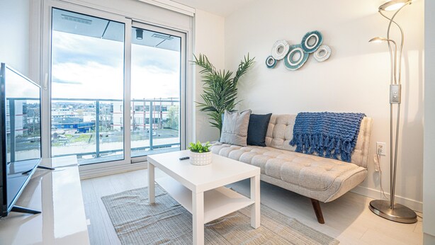 A modern living room with a sofa, a coffee table, a floor lamp, and a large window offering a city view. - Spacious 3-bedroom apartment with AC, WiFi in wonderful Vancouver (Vancouver)