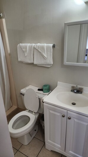 Een bad/douchecombinatie, handdoeken, toiletpapier