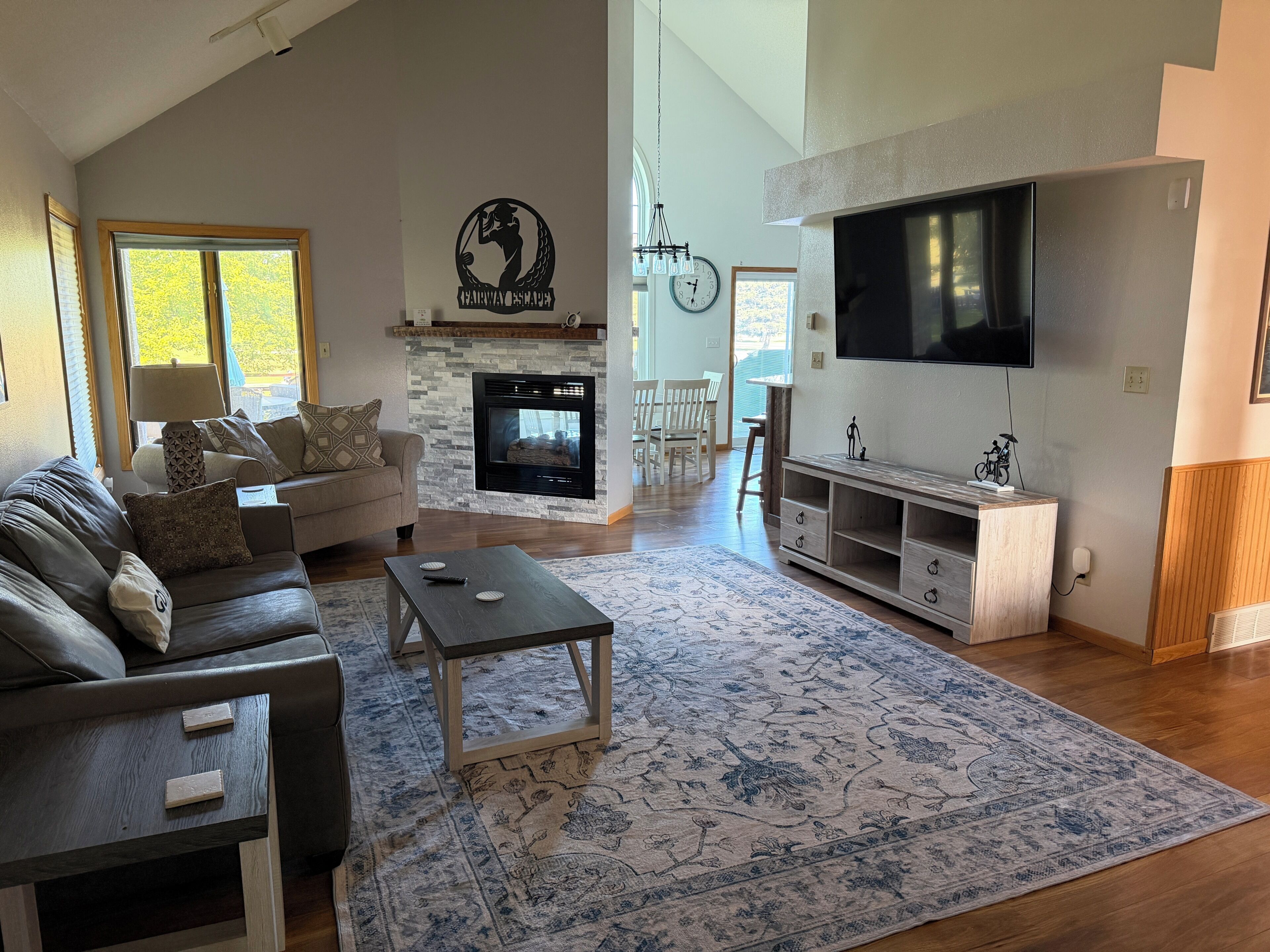 Un salon avec une cheminée, un canapé, une table basse, un téléviseur et un coin repas.