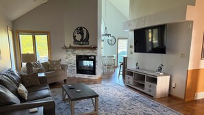A living room with a fireplace, sofa, coffee table, TV, and a dining area. - The Fairway Escape – Spacious 6BR Golf Course Retreat, Walk to Downtown Hayward! (Hayward)