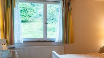 Ein Schlafzimmer mit Fenster, Heizkörper, Nachttisch und Lampe.