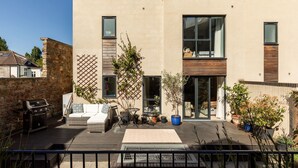 A modern house with a patio, outdoor furniture, and a barbecue grill.