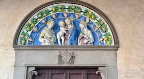 A detailed fresco with religious figures and a decorative border of fruits and leaves.