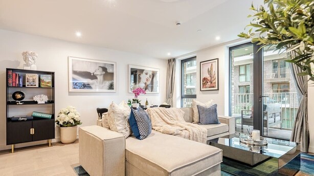 A modern living room with a sectional sofa, a glass coffee table, and a bookshelf. - Modern Luxury Apartment in London’s Historic Heart (London)