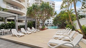 Zona de piscina con sillones blancos y una alberca.
