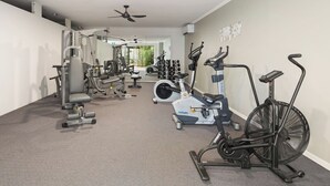 Un gimnasio con diverso equipo de ejercicio, incluyendo cintas de correr, bicicletas estáticas y máquinas de pesas.