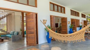 Un hall d’entrée spacieux, doté d’un hamac, de meubles en bois et de grandes fenêtres.