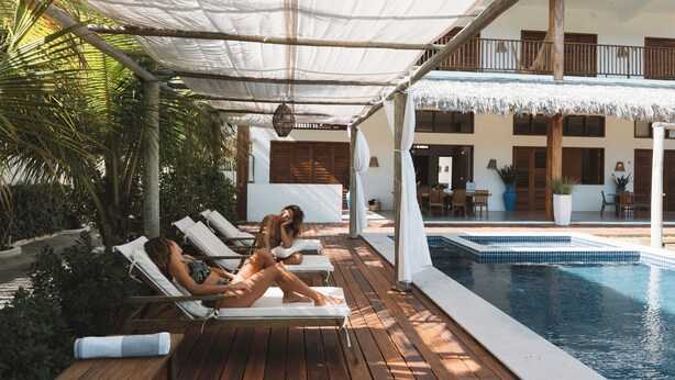 Un espace aménagé au bord de la piscine, avec des chaises longues, une piscine et un patio couvert.