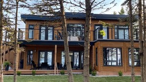 Una casa moderna de dos pisos con amplios ventanales y fachada de madera.